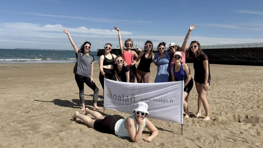 Enterrement de vie de jeune fille - photo de groupe sur le sable - bannière hoalañ - mariée allongée devant la bannière