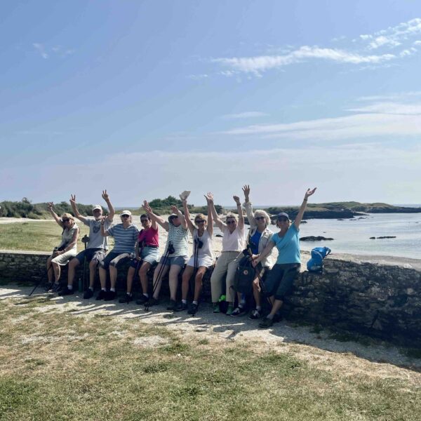 Personnes assises sur un muret avec paysage marin